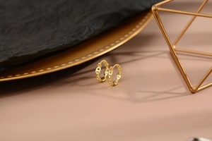 Dettaglio di orecchini a maglia placcati in oro su sfondo decorativo caldo