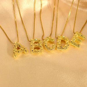 Detail der Goldbuchstaben-Anhänger A bis E mit einzigartiger lavaartiger Oberflächenstruktur