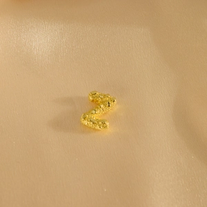 Detailaufnahme des goldenen Z-Anhängers mit glitzernder Textur auf Seidenhintergrund