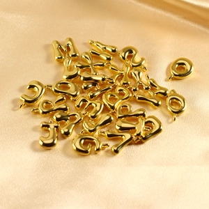 Close-up of golden bubble letter charms with polished finish on elegant champagne satin
