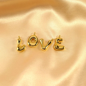 Close-up of golden bubble letter charms spelling LOVE on a satin background