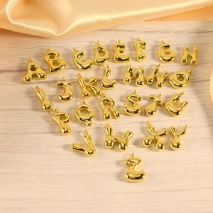 Macro view of 26 gold 3D bubble alphabet pendants arranged on light wood texture