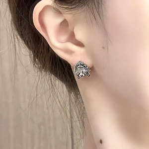 Close-up of vintage silver cat head stud earring with ethnic bohemian design