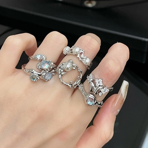 Detail of silver rings set with pearls and moonstones on model hand with black background