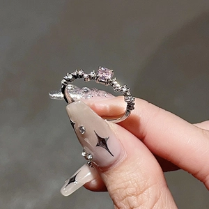 Makroaufnahme von rosa herzförmigem Kristallring mit Wellenband und glitzernden Steinen