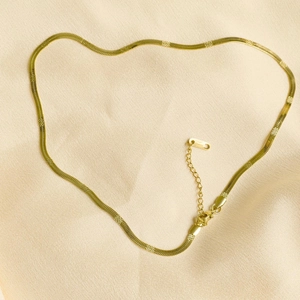 Détail du collier chaîne serpent dorée montrant la texture polie et le fermoir mousqueton