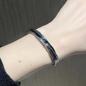 Macro detail of silver open cuff bracelet featuring liquid lava texture on wrist
