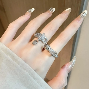 Dettaglio di anelli argentati con fiocco e fibbia in zircone indossati da una modella
