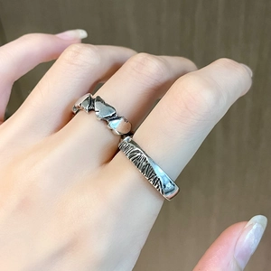 Détail de bagues vintage cœur et texturées avec finition argent mat portées au doigt
