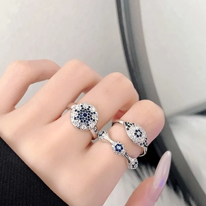 Detail of three-piece silver ring set featuring Evil Eye design worn on a model's fingers