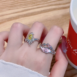 Exquisite Ringe mit rosa Emaille-Blume und gelbem Zirkon auf Holzoberfläche
