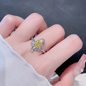 Detailansicht des unregelmäßigen Vogelrings mit gelbem Zirkon am Finger und Strickärmel