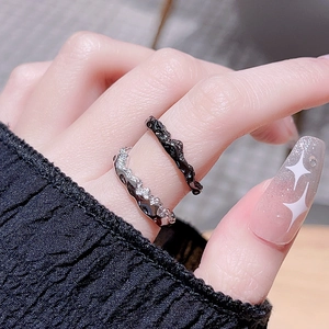 Close-up of black enamel and silver rhinestone wave rings set on a model hand