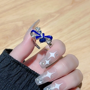 Detailed close-up of a blue enamel bow ring with crystals worn on a finger
