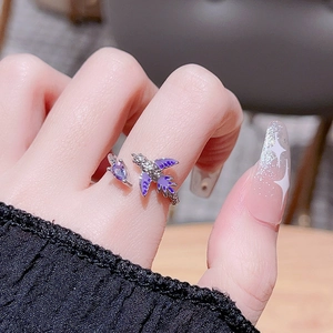 Close-up of a purple enamel swallow ring with silver zircons worn on a finger