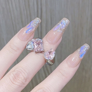 Nahaufnahme von rosa Kristallen auf verstellbarem Silberring mit Nailart-Hintergrund
