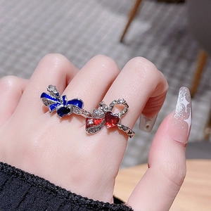 Detail shot of blue and red enamel bow rings with heart-shaped gemstones and zircons