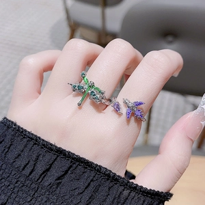 Detail of an open ring featuring a green dragonfly and purple bird with colored zircons