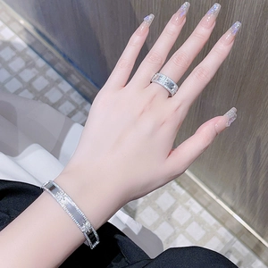 Gros plan d'un bracelet et d'une bague en argent avec motif trèfle pavé de diamants