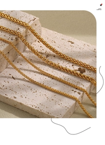 Close-up of golden wheat link necklaces in four widths on travertine stone