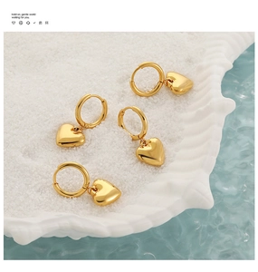 Detailopname van gouden roestvrijstalen hartjes oorbellen op een decoratieve schelp