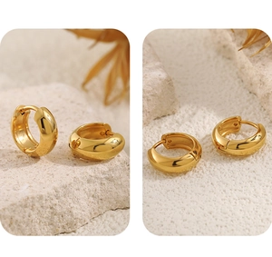 Detailed view of polished gold stainless steel chunky hoop earrings on textured stone