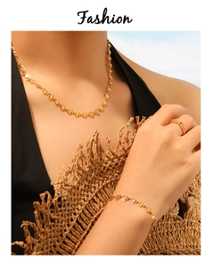 Detalle de conjunto de collar, pulsera y anillo de corazón dorado en modelo