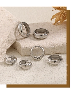 Polished stainless steel hoop earrings in various sizes on a decorative stone base