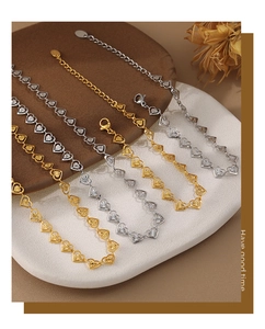 Detalle del collar con colgante de corazón dorado con diseños grabados y cierre de mosquetón