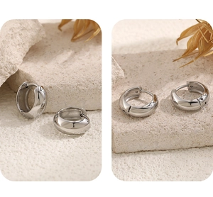 Detailed view of polished stainless steel hoop earrings on a minimalist stone base
