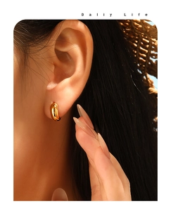 Polished chunky gold hoop earrings in stainless steel shown on model for daily life