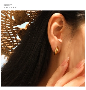 Close-up of a polished gold hoop earring worn by a model in warm natural light