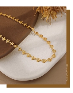 Detalle de collar de eslabones de corazón dorado con textura de rayos de sol en piedra