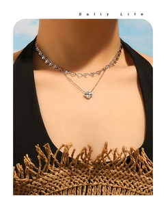 Detalle de collar de doble capa con cadena de corazones y colgante de trébol en modelo