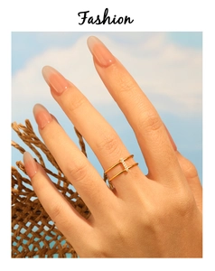 Detail of a 24K gold plated double-band ring with inlaid crystals worn by a model outdoors