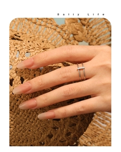 Detail of silver double-layered ring with inlaid zircon on textured straw background
