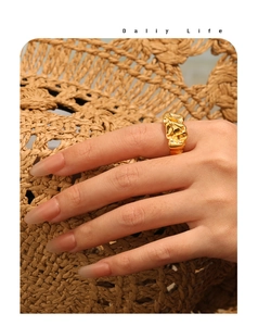 Detail eines Goldrings mit Lavatextur an einem Modell vor gewebtem Strohhut Hintergrund