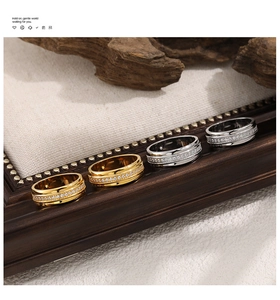 Detailed view of four gold and silver band rings with inlaid zircon on a wooden frame