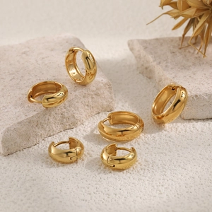 Three pairs of polished gold stainless steel hoop earrings in varying sizes on stone