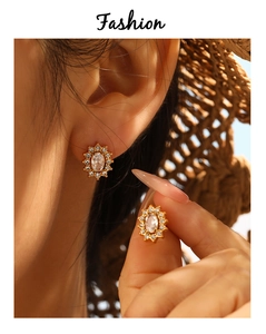 Macro shot of gold sun flower stud earrings with sparkling clear oval zircon crystals