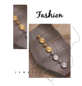 Detail shot of gold and silver sunburst oval pendants on a textured stone tray