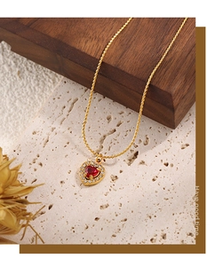 Detailed close-up of 18K gold heart necklace with red gemstone and white zircons
