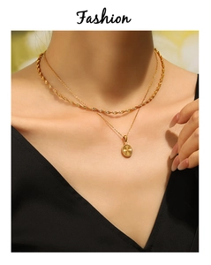 Detail of double-layered gold plated necklace with radial pattern round pendant and rope chain