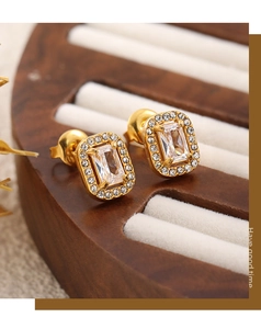 Detailed macro view of gold plated earrings featuring emerald-cut cubic zirconia and pavé stones