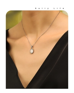Detailed close-up of oval sunburst pendant with beaded edge on silver chain