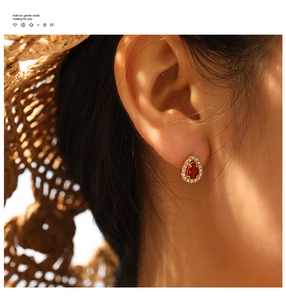 Detail of teardrop ruby earring with crystal halo on ear with warm sunlight