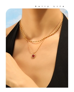 Detail of 18K gold-plated double-layer necklace with a round red zircon heart pendant