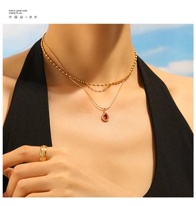 Detailed macro view of 18K gold-plated double-layer necklace with red teardrop pendant