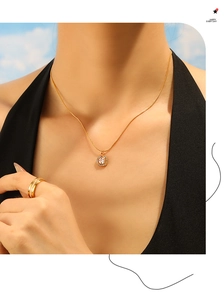 Close-up of gold titanium necklace with square zircon pendant worn by a model