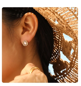 Close-up of vintage gold square stud earrings with zircons in a summer sunlight scene
